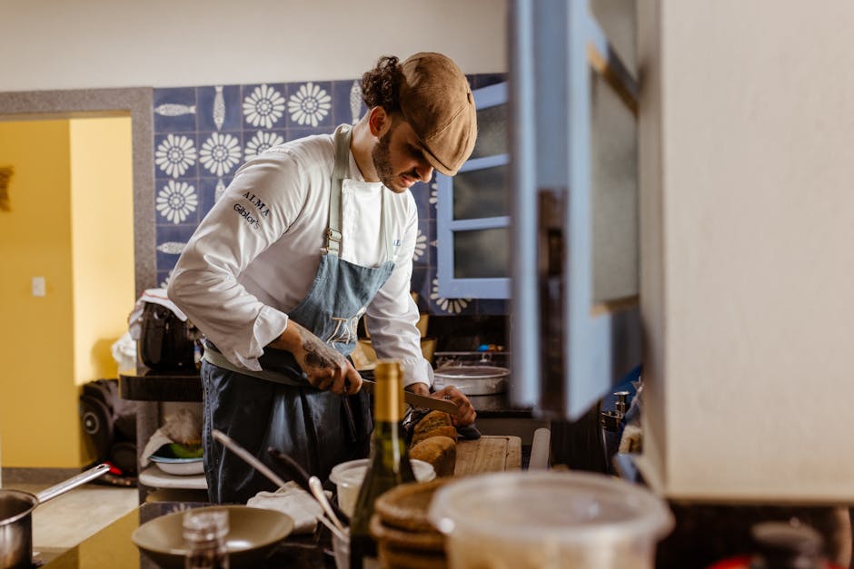 Chef wearing uniform and cap slicing bread in a contemporary kitchen setting