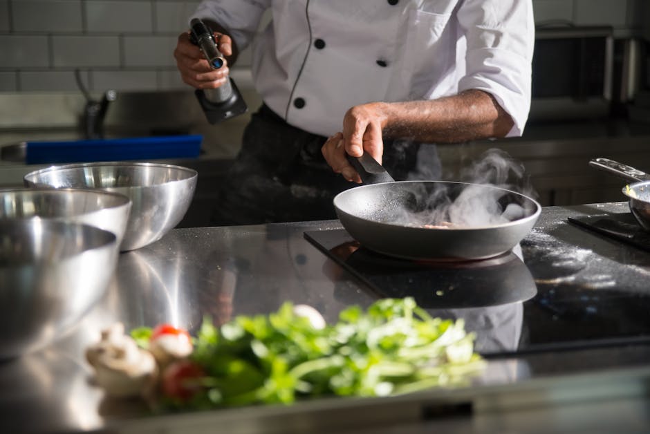 Chef prepares food in a sleek kitchen using a frying pan on an induction cooktop