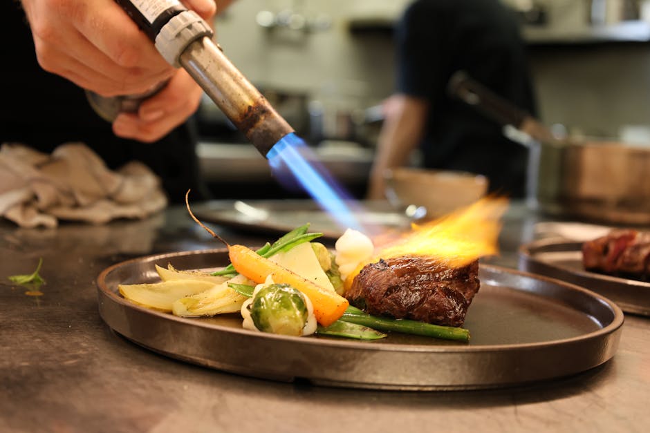 Searing gourmet dish with fresh vegetables using a culinary torch in a professional kitchen
