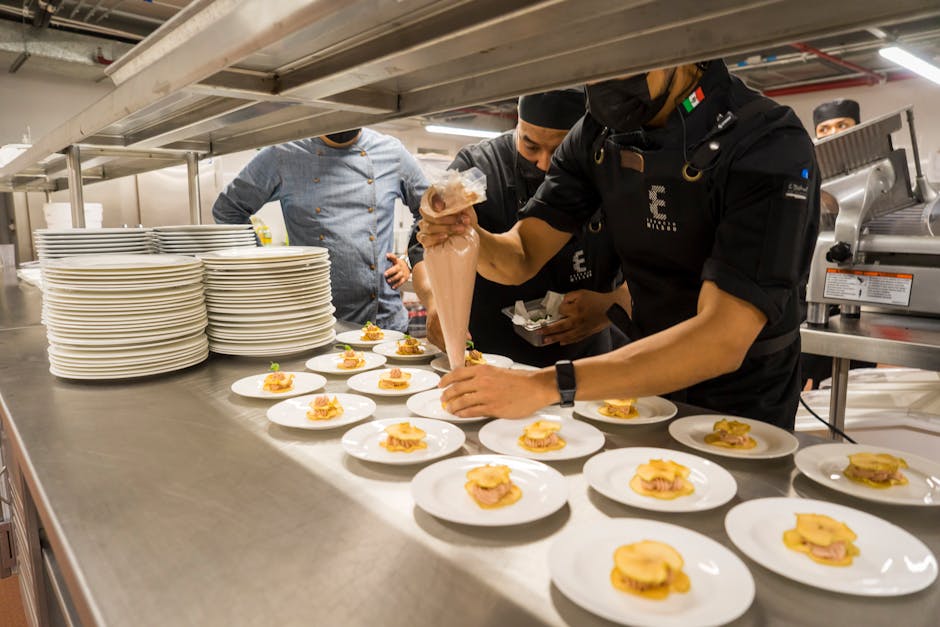 Chefs work meticulously plating gourmet dishes in a bustling professional kitchen