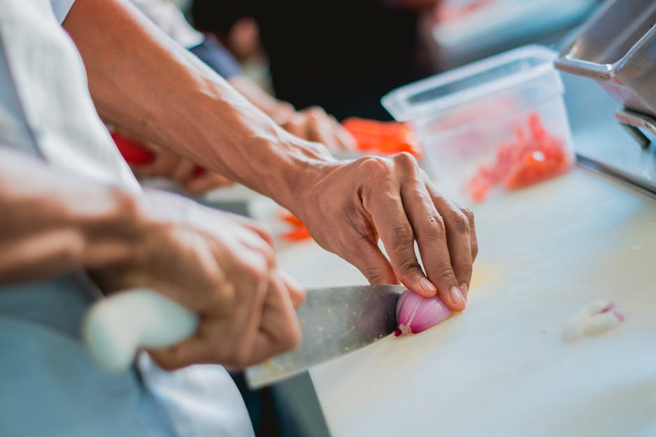 Close-up of a chef slicing onion in a kitchen setting, emphasizing food preparation