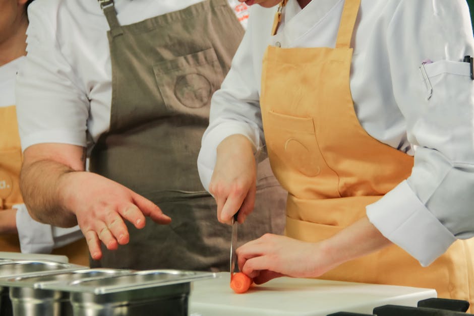 Close-up of chefs chopping carrots in a modern kitchen setting