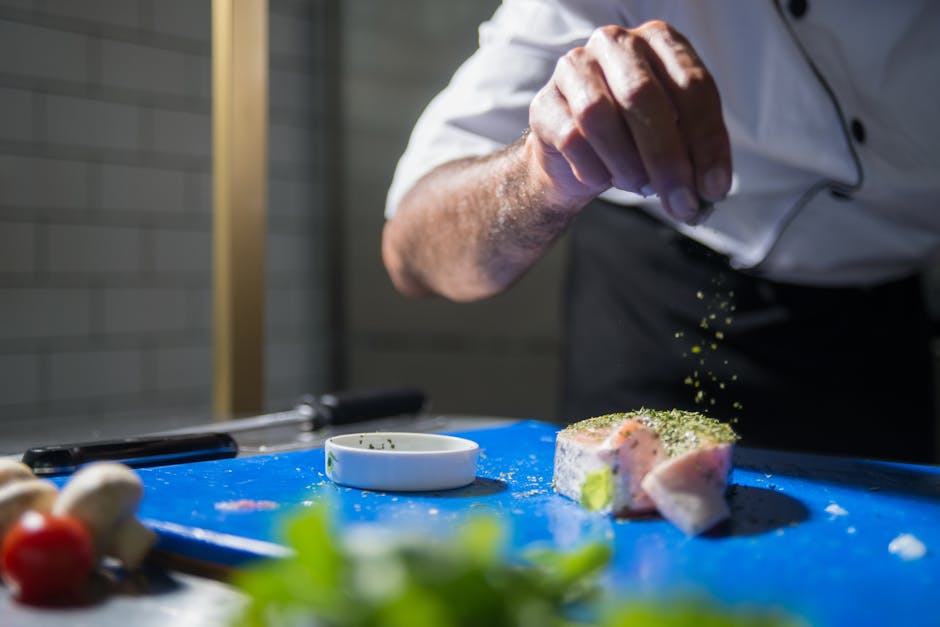 A chef skillfully seasons a gourmet dish in a modern kitchen, highlighting culinary expertise
