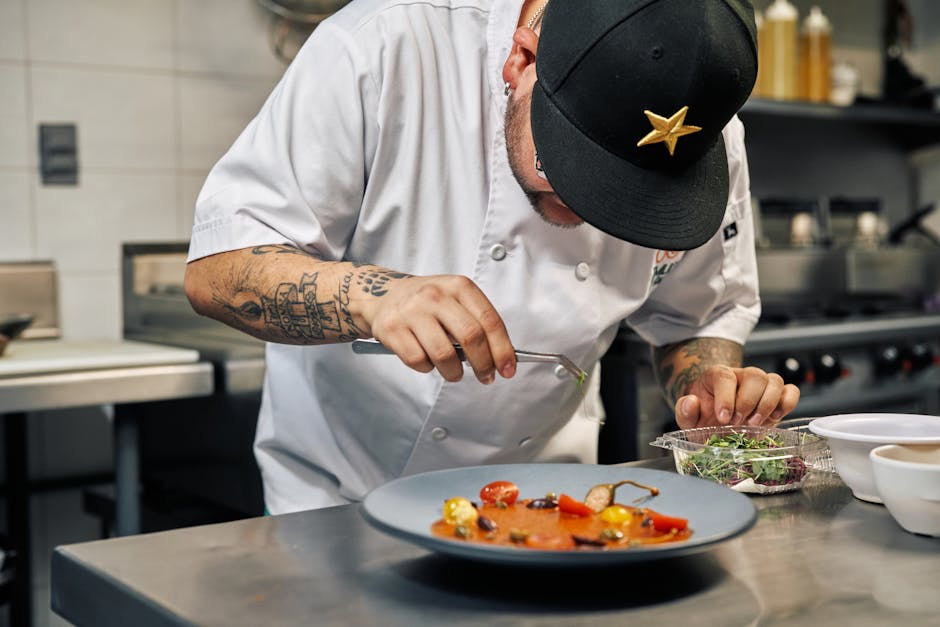 Close-up of a chef in a professional kitchen garnishing a gourmet dish with precision