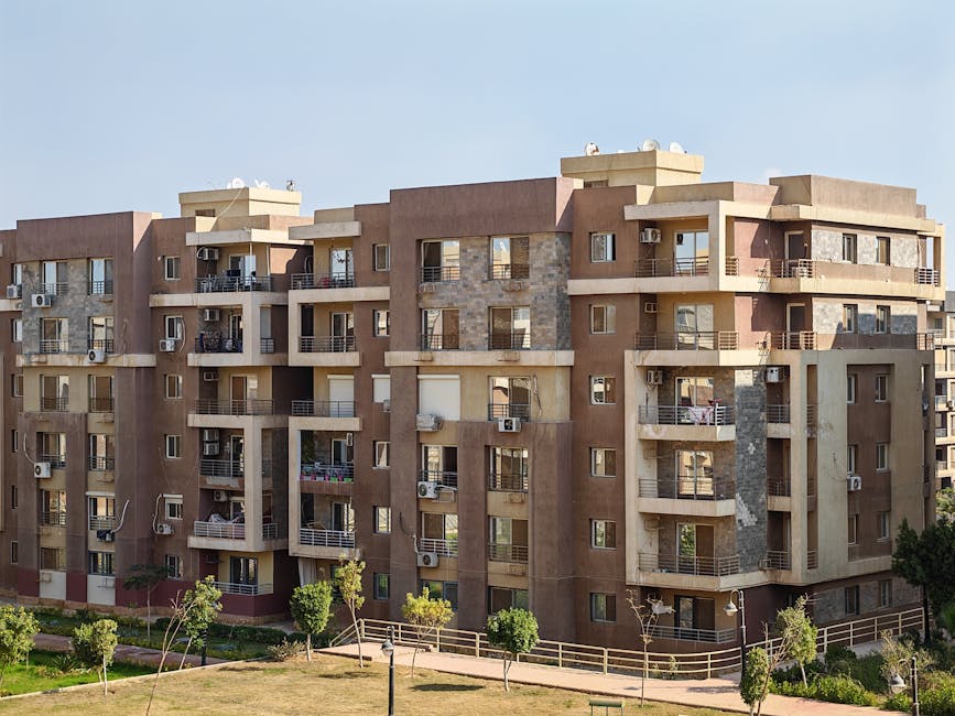 Contemporary multi-story apartment building with balconies in a sunny urban setting.